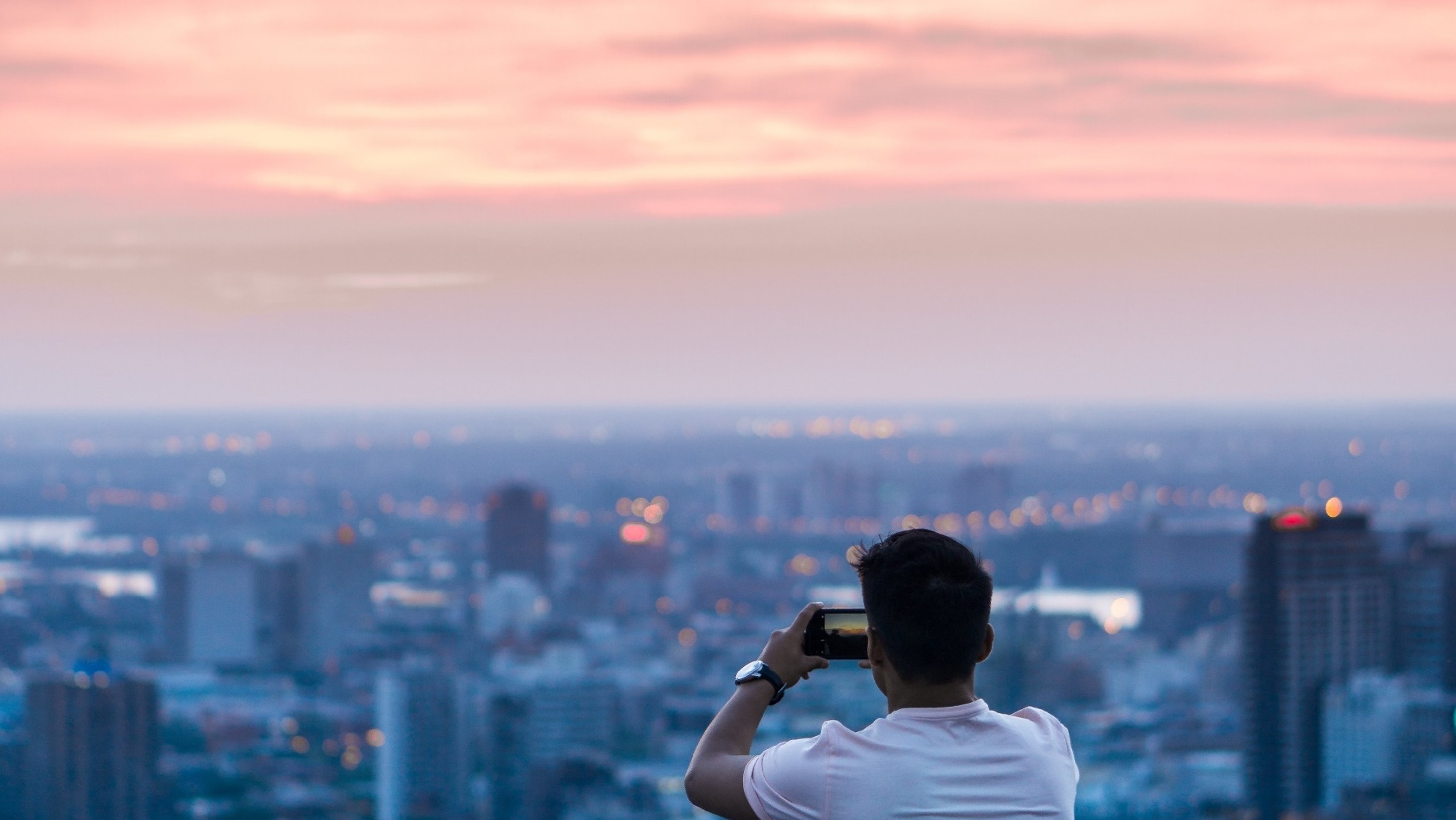 Mann fotografiert die Skyline einer Stadt mit seinem Smartphone.