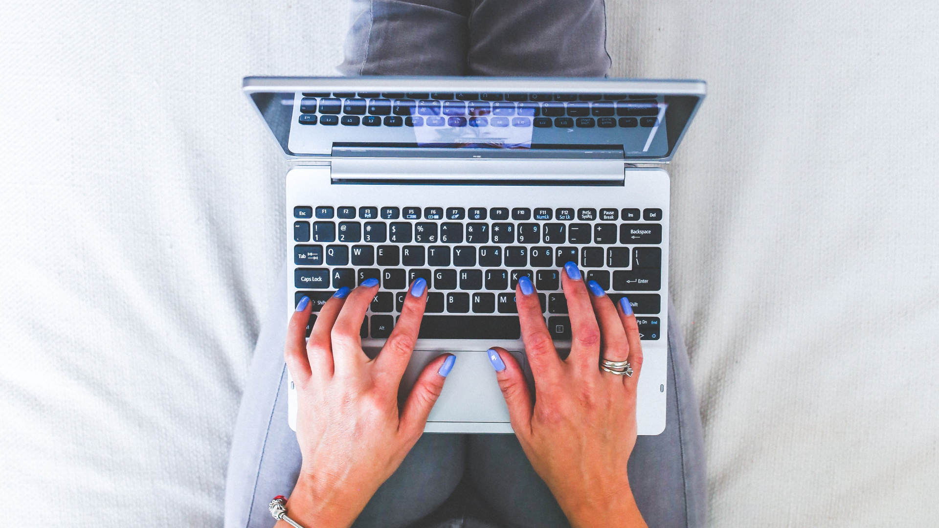 Frau sitzt auf Couch und arbeitet am Laptop