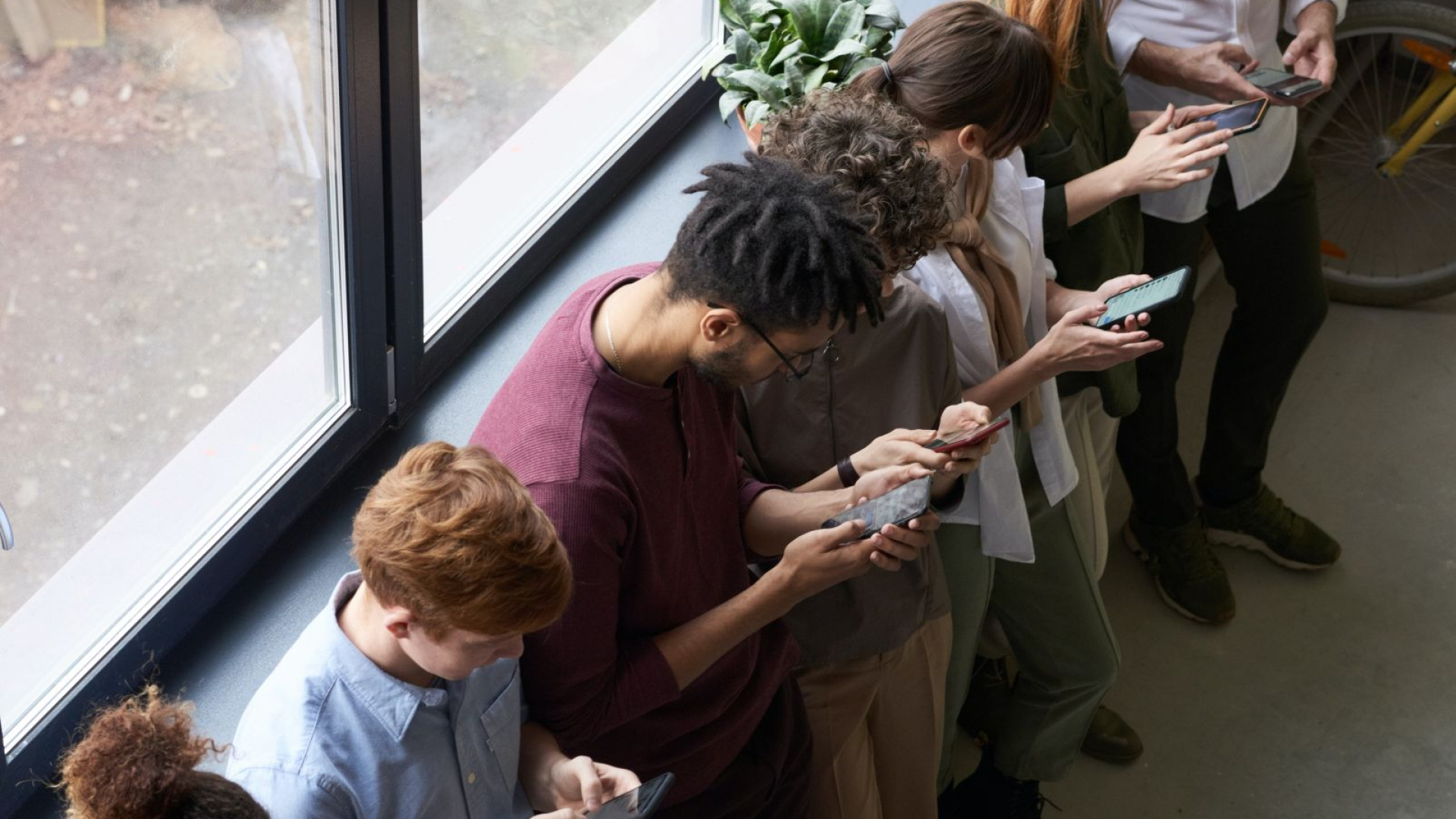 aufs Smartphone guckende Menschen am Fenster