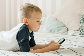 Junge im Bett mit Smartphone