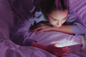 junge Frau mit Smartphone im Bett