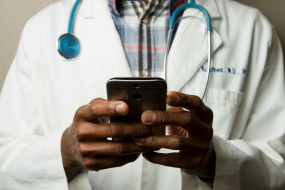 Ein Arzt mit Handy in der Hand als Sinnbild für das Get Started Health Network zum Thema DiGa