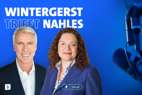 Ralf Wintergerst und Andrea Nahles stehen nebeneinander vor einem blauen Hintergrund mit dem Text „WINTERGERST TRIFFT NAHLES“. Wintergerst lächelnd mit kurzen weißen Haaren und einem dunklen Anzug mit weißem Hemd. Nahles mit lockigen braunen Haaren, einer Brille und einem blauen Blazer über einer gemusterten Bluse. Rechts im Bild sind ein schwarzes Mikrofon und große Kopfhörer sichtbar. Ein „Podcast“-Symbol ist unten eingeblendet.