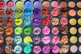 Eine Palette mit einer Vielzahl kreisförmiger Lidschatten in verschiedenen Farben, von kräftigen Rottönen über Blau, Grün, Gelb, Lila bis hin zu Erdtönen und Gold.