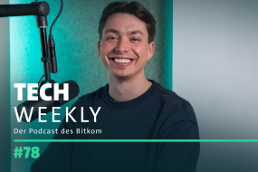 Tech Weekly - Titelbild der Podcast-Episode 78: Daniel Breitinger, Bitkom-Startup-Experte mit kurzen braunen Haaren und dunkelblauem Pullover sitzt vor einem schwarzen Mikrofon mit Popschutz und lächelt breit in die Kamera.