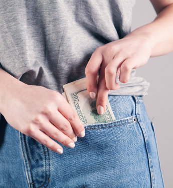 Eine Frau zieht einen Geldschein auf ihrer Hosentasche