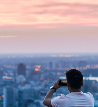 Mann fotografiert die Skyline einer Stadt mit seinem Smartphone.