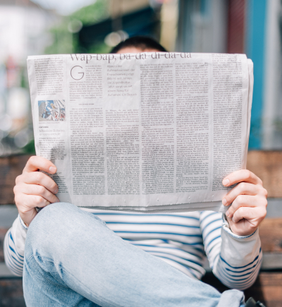 Person sitzt auf einer Bank und liest Zeitung