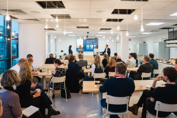 Agrarpolitisches Frühstück - Impressionen: Einblick in den modernen Bitkom-Veranstaltungsraum mit großen Fenstern, weißen Wänden und hängenden Glühbirnen.